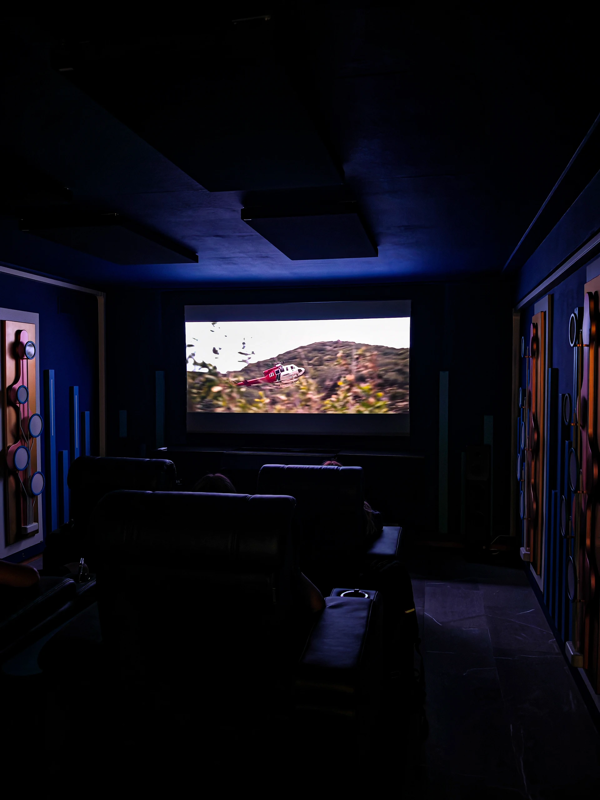 Sala cinema privata sul Lago d’Orta — Cinema attivo Sala del Lago d’Orta vista dal retro, con proiezione attiva e illuminazione blu attenuata.