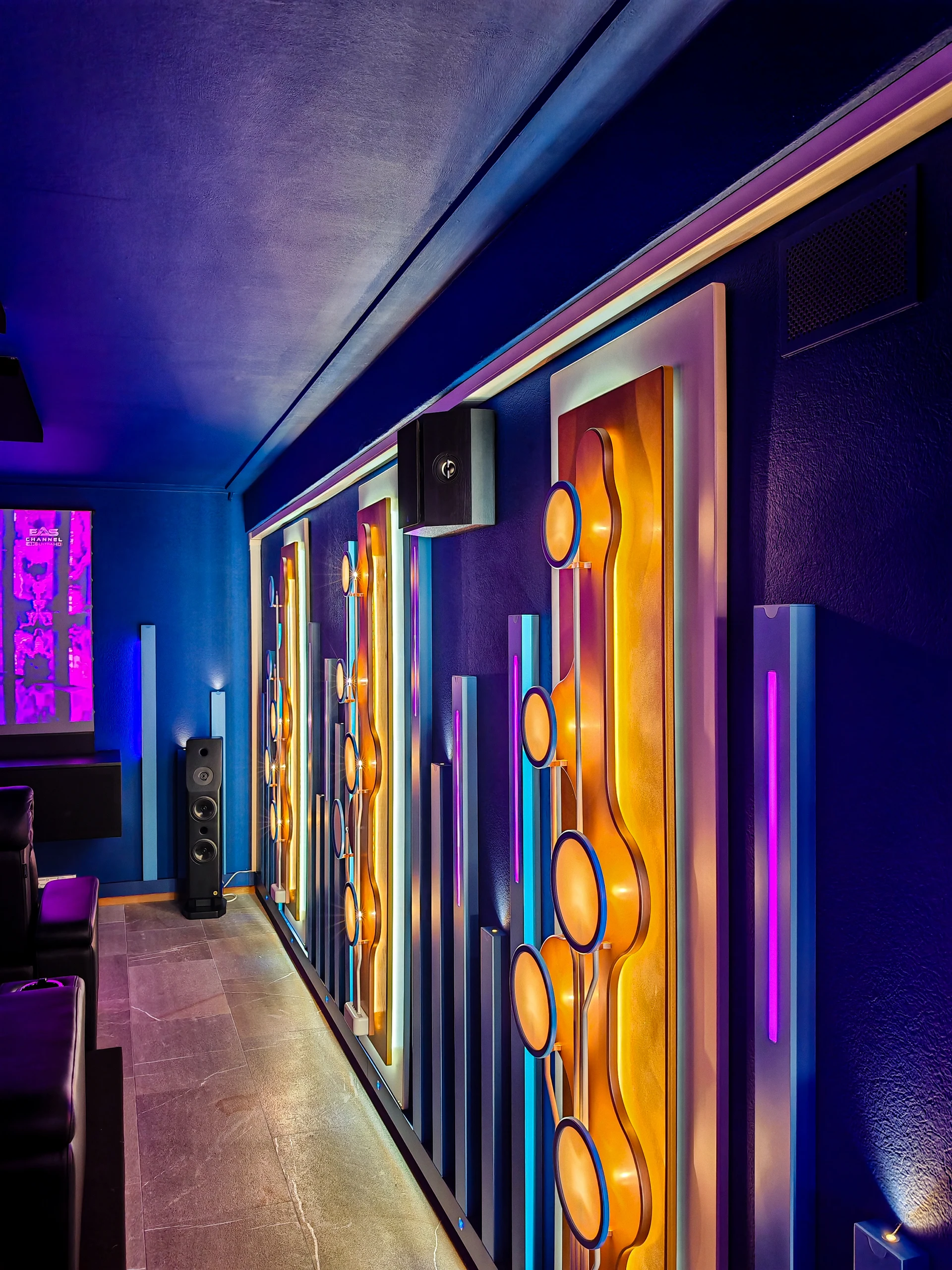 Parete laterale del cinema sul Lago d’Orta, con pannelli decorativi, diffusori e luce colorata.