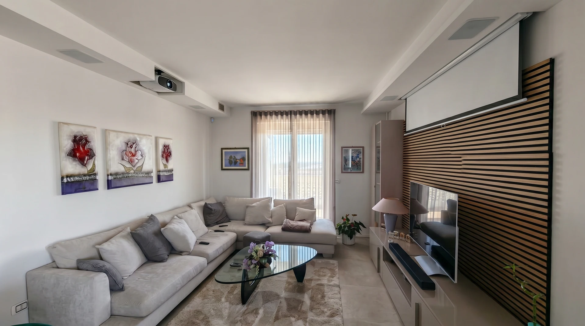 Living con proiettore a soffitto e schermo davanti alla parete in legno.