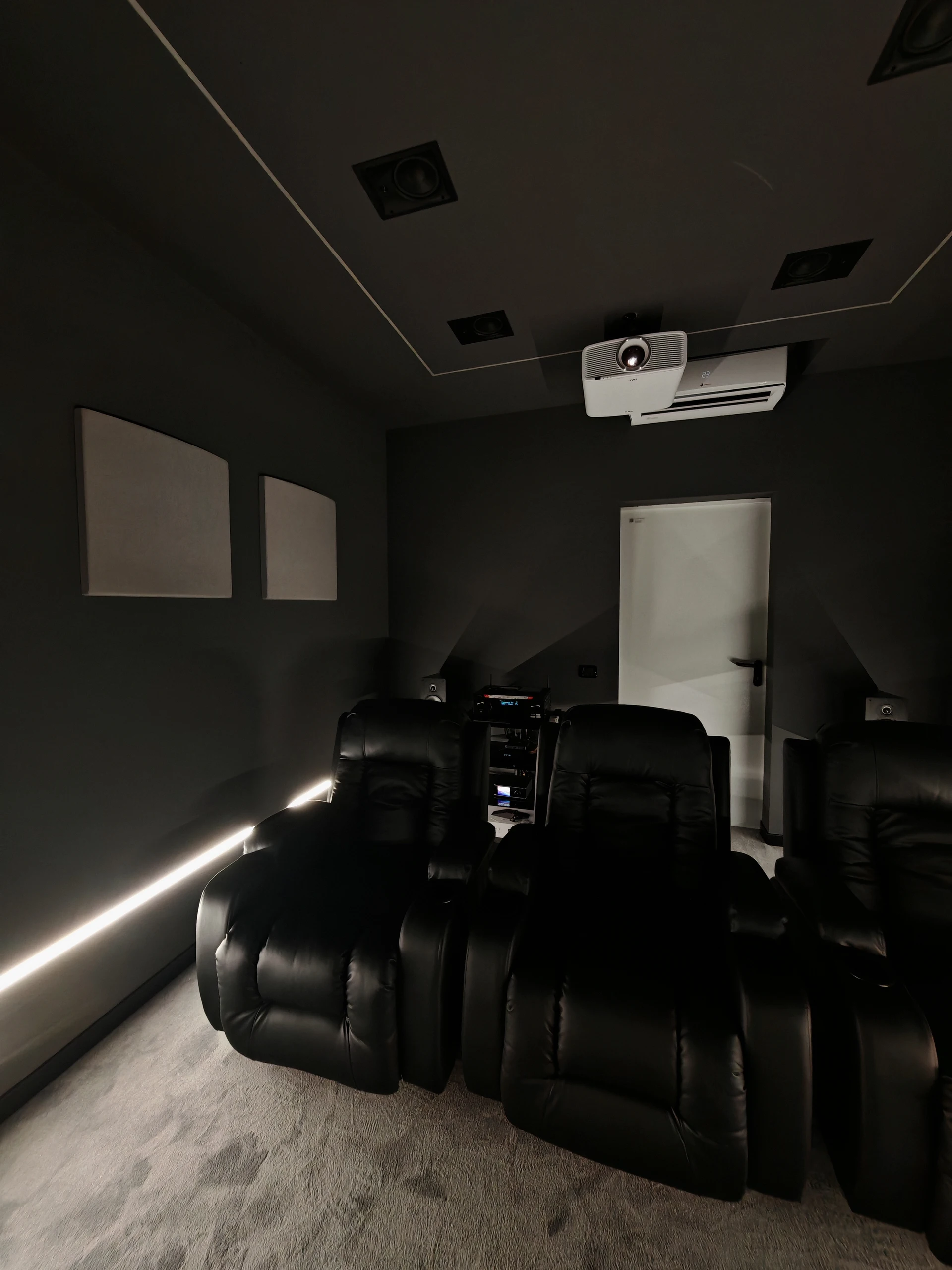 Retro della sala cinema di Volpiano con proiettore a soffitto, diffusori e poltrone reclinabili.