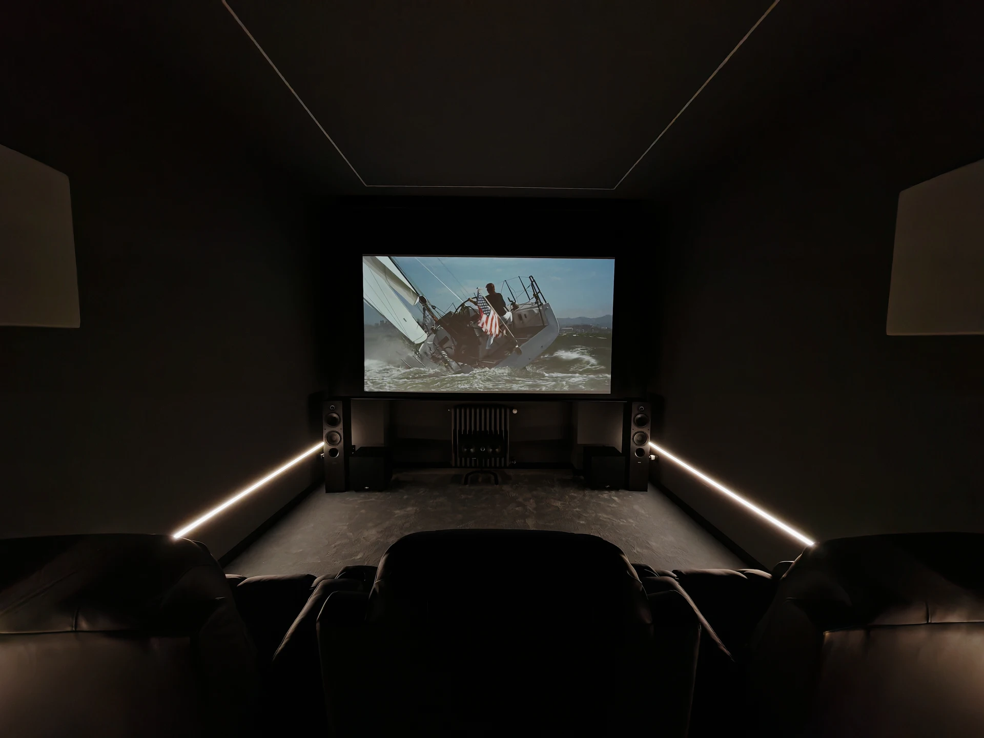 Sala cinema di Volpiano vista dalle sedute, con proiezione attiva e strip LED lungo le pareti.